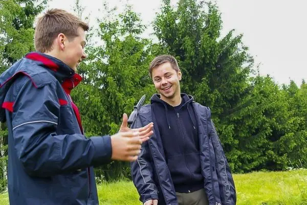 Zwei Personen unterhalten sich im Freien vor grünen Bäumen