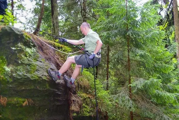 Abseilen an einem Felsen mit Seil und Sicherungsgurt im Wald