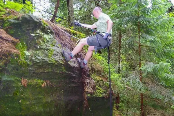 Abseilen an einem Felsvorsprung mit Seil und Sicherungsgurt