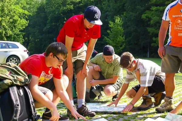 Fünf Personen beugen sich über eine Karte auf dem Boden