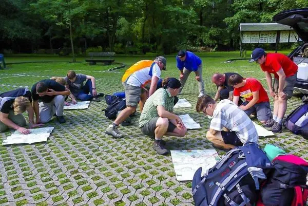 Gruppe betrachtet Karten auf dem Boden, Rucksäcke liegen daneben