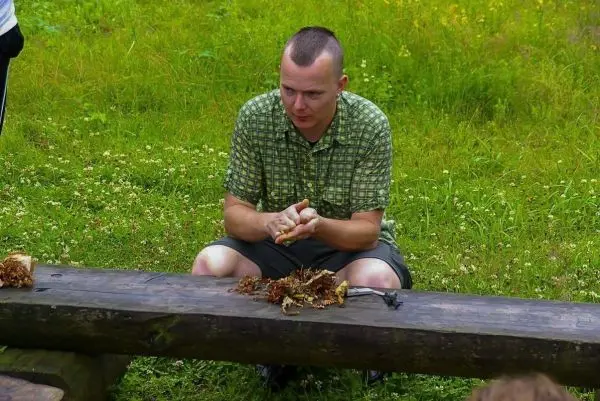 Mann bearbeitet Zunder auf einer Holzbank im Freien