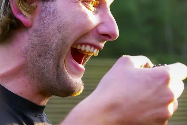 Mann hält etwas in der Hand und lacht laut