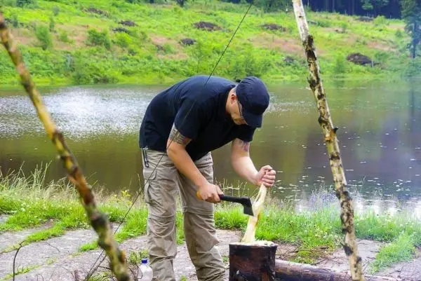 Messer bearbeitet Holzstück auf einem Baumstamm am Ufer eines Gewässers