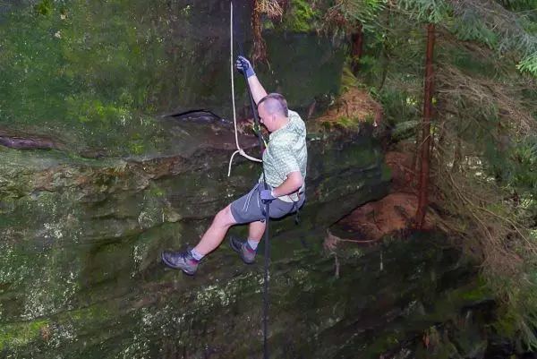 Person klettert an einer Felswand mit Seilunterstützung