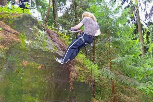 Person seilt an einem Felsen in den Wald ab beim Überlebenstraining