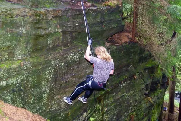 Person seilt an einem Felsvorsprung mit einem Seil ab