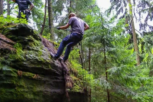 Person seilt an einer Felswand im Wald ab