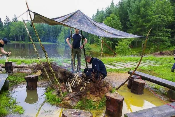 Tarp-Notunterkunft schützt über Feuerstelle mit Zunder und Holz