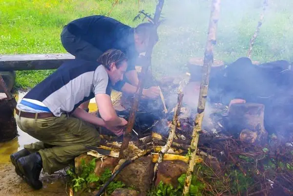Zunder glimmt über einem kleinen Bodenfeuer zwischen Steinen und Ästen