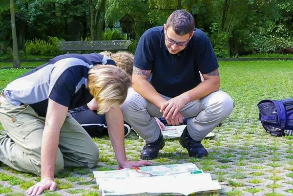 Zwei Personen betrachten eine Karte auf dem Boden in einem Park