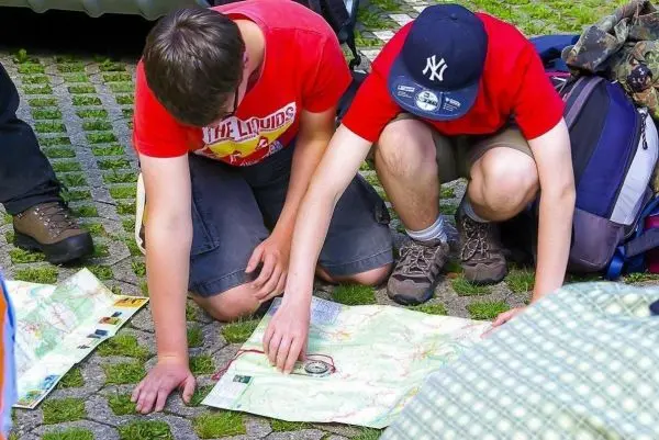 Zwei Personen studieren eine Karte und nutzen einen Kompass zur Orientierung