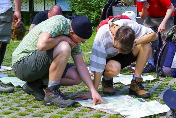 Zwei Personen studieren Karten auf dem Boden, während andere im Hintergrund stehen