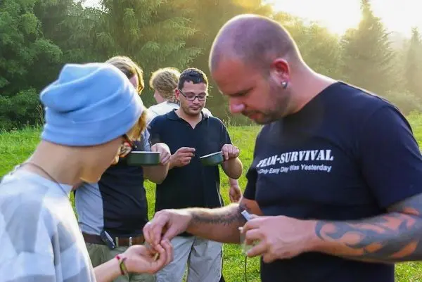 Zwei Personen tauschen Materialien aus, während andere im Hintergrund stehen