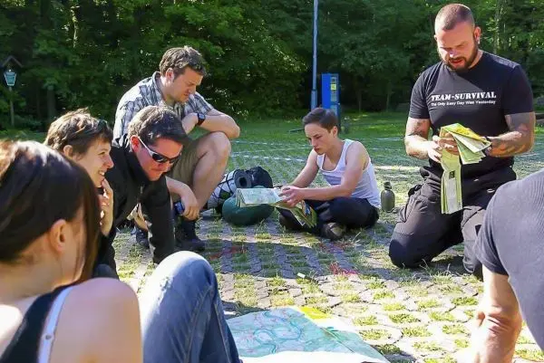 Gruppe betrachtet Karten und diskutiert Orientierungstechniken auf dem Boden