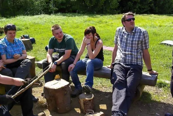 Gruppe sitzt auf Baumstämmen und unterhält sich im Freien