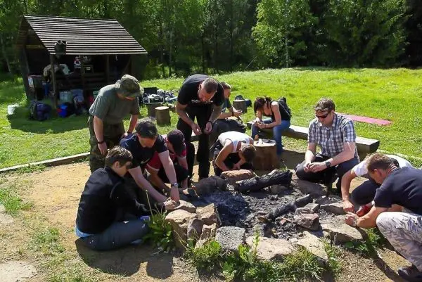 Gruppe übt Feuerentzündung mit Zunder und Funken am Lagerfeuer