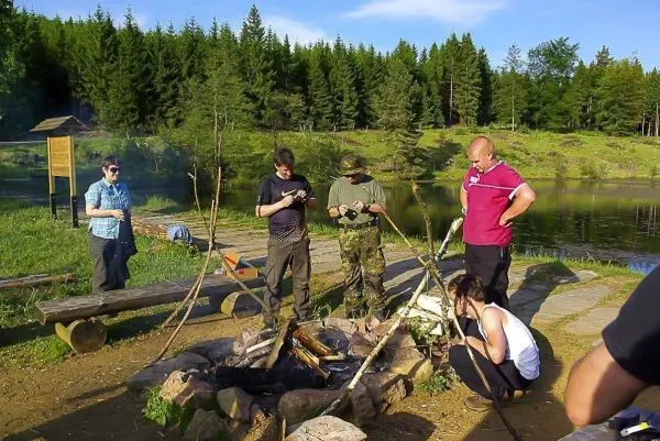 Gruppe um ein Feuer versammelt, Holz wird vorbereitet und Zunder angezündet