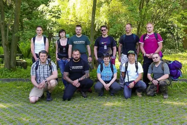 Gruppierung von zehn Personen in Outdoor-Bekleidung auf einer Wiese