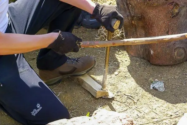 Holzstück wird mit einem Stock bearbeitet, um Reibung zu erzeugen