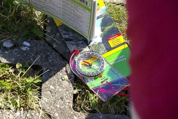 Kompass liegt auf einer Landkarte im Gras beim Orientieren