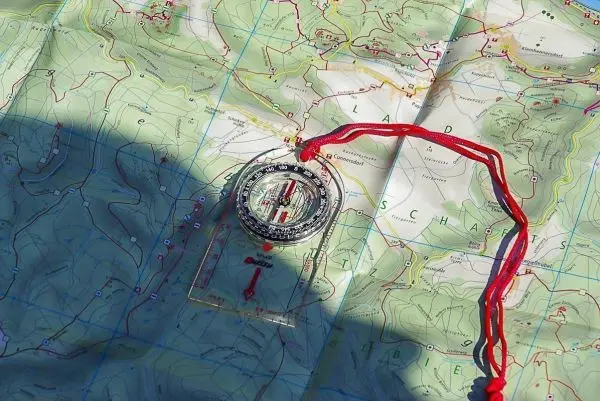 Kompass liegt auf einer topografischen Karte mit Höhenlinien und Markierungen