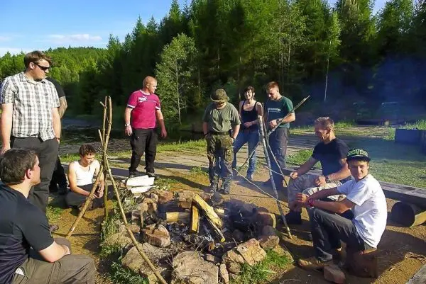 Kreis aus Steinen um ein kleines Feuer, mehrere Personen stehen und sitzen darum