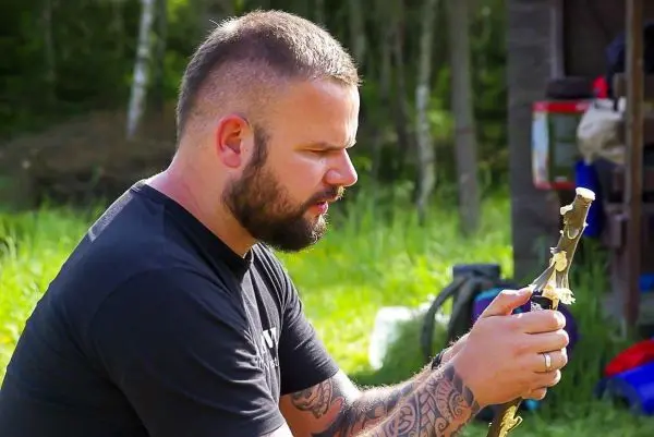 Mann bearbeitet einen Stock mit einem Messer im Freien