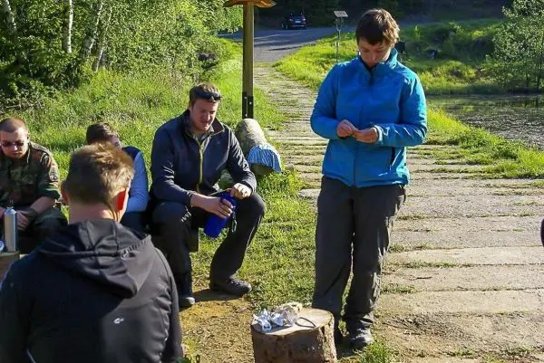 Mann bereitet Essen auf einem Holzstück vor, während andere zuschauen