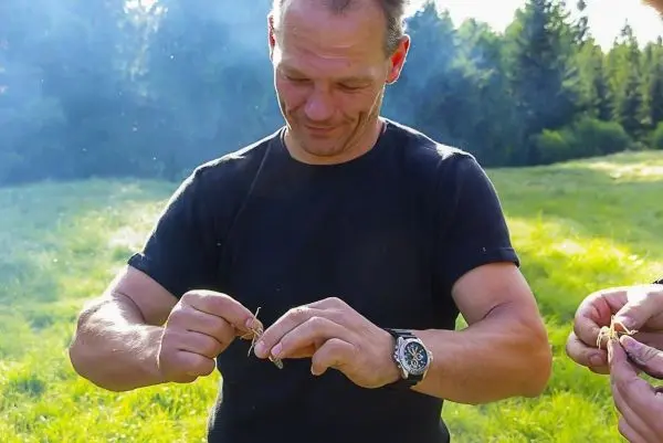 Mann bereitet Zunder aus Pflanzenmaterial für ein Feuer vor