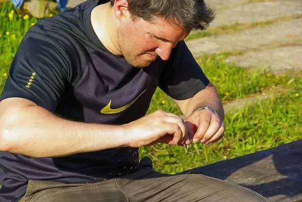Mann bindet eine Schnur an einen Haken auf einem Holzstück