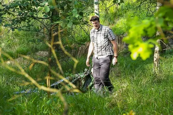 Mann geht durch hohes Gras und Bäume in einem Waldgebiet