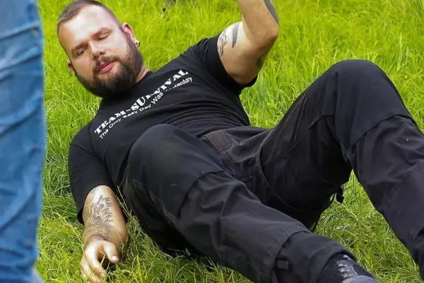 Mann liegt auf dem Gras und hebt einen Arm an