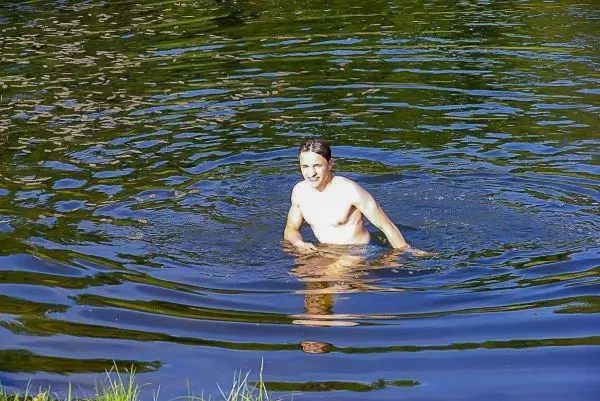 Mann steht im Wasser und erzeugt Wellen mit seinen Bewegungen