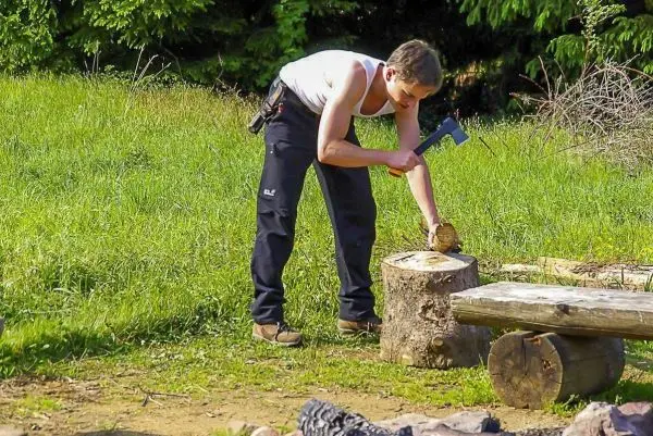 Person hackt mit einer Axt Holz auf einem Baumstumpf