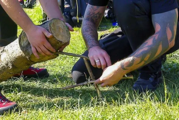 Zwei Hände konstruieren eine Schlagfalle (Figure-Four) mit Holzstücken