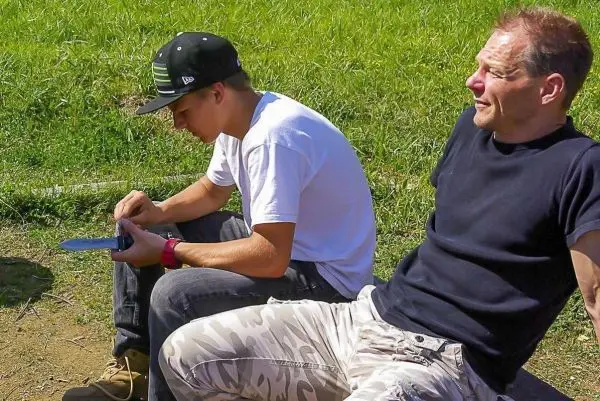 Zwei Personen sitzen auf dem Boden und schauen auf ein Gerät