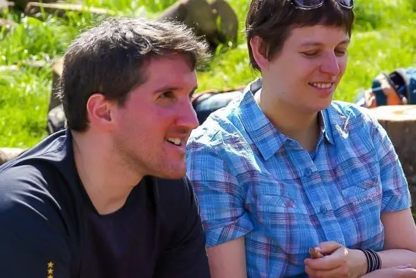 Zwei Personen sitzen lächelnd auf dem Boden und unterhalten sich