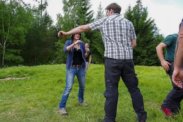 Zwei Personen üben eine Technik zur Selbstverteidigung auf einer Wiese