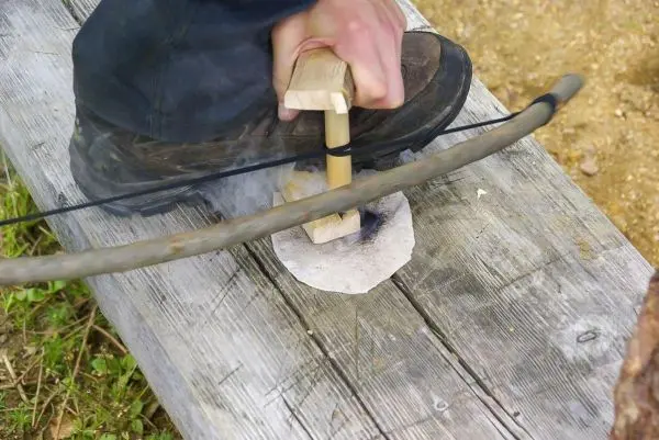 Bogenfeuerbohrer erzeugt durch Druck und Drehung Funken auf Zunder