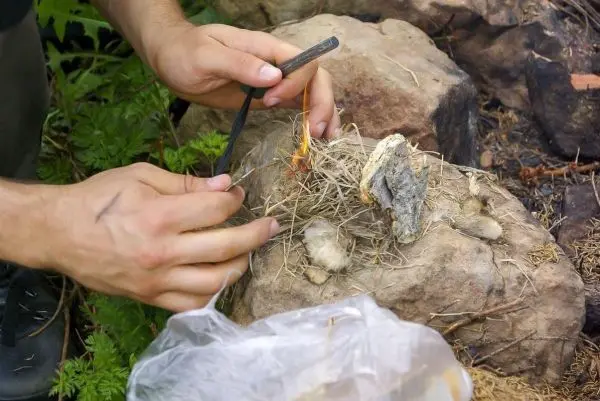 Feuerstahl erzeugt Funken auf Zunderhaufen aus Gras und Rinde