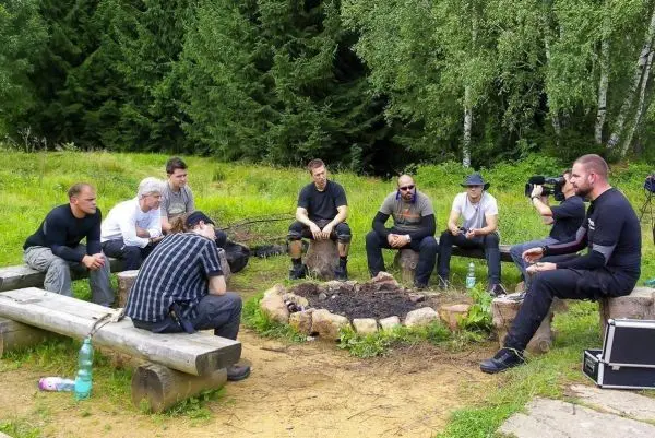 Gruppe sitzt um ein kleines Bodenfeuer auf Baumstämmen in der Natur