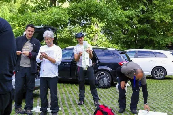 Gruppierung von vier Personen, die Ausrüstung und Karten an einem Parkplatz überprüfen