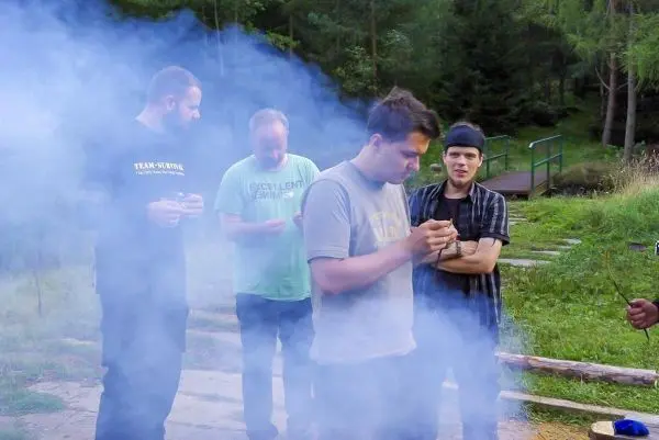 Gruppierung von vier Personen in Rauch, eine Person hält Zunder in der Hand