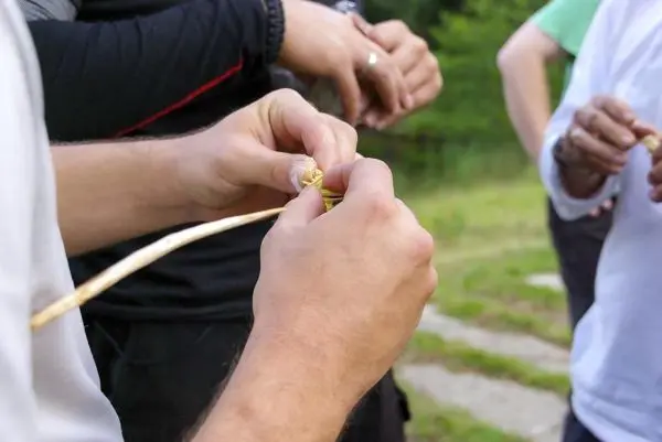 Hände formen eine Schnur aus Pflanzenmaterial