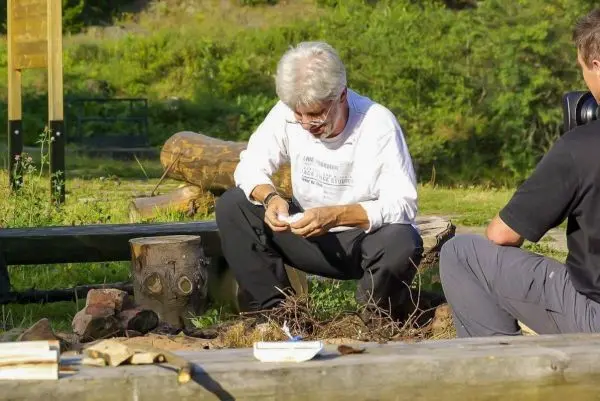 Mann bearbeitet Holzstück mit einem Messer auf einer Holzbank