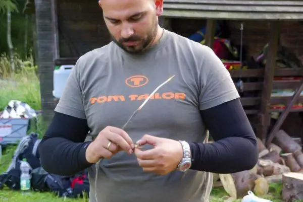 Mann bindet einen dünnen Stock mit Schnur zusammen