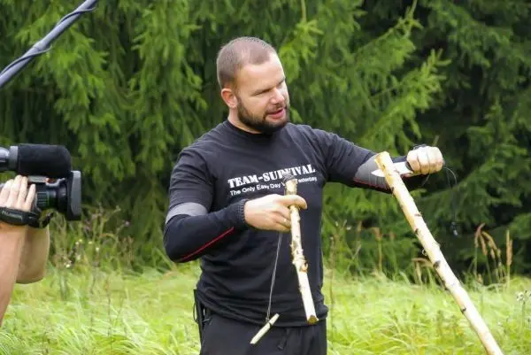 Mann demonstriert zwei Holzstücke zur Herstellung einer Schlagfalle