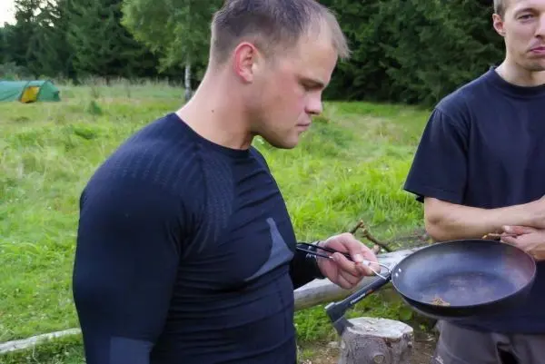 Mann hält Pfanne mit Nahrung und schaut konzentriert darauf