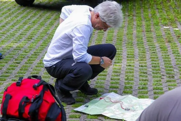 Mann kniet neben einer Karte und studiert die Route